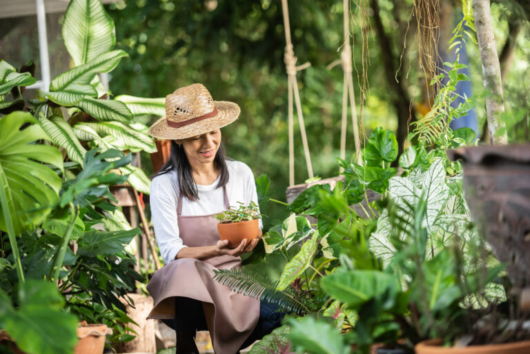 Attractive young woman working with decorative plants in garden